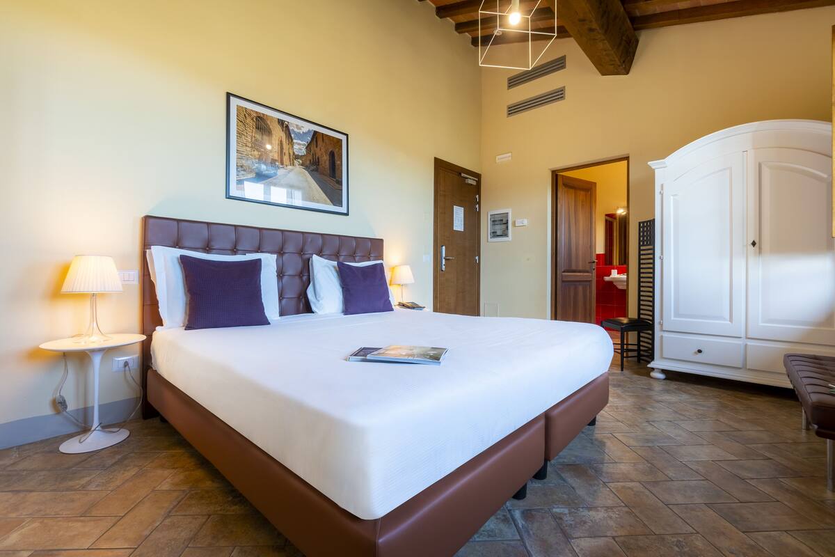 Une chambre d’hôtel avec un grand lit, des lampes de chevet, un tableau encadré au mur et une armoire.