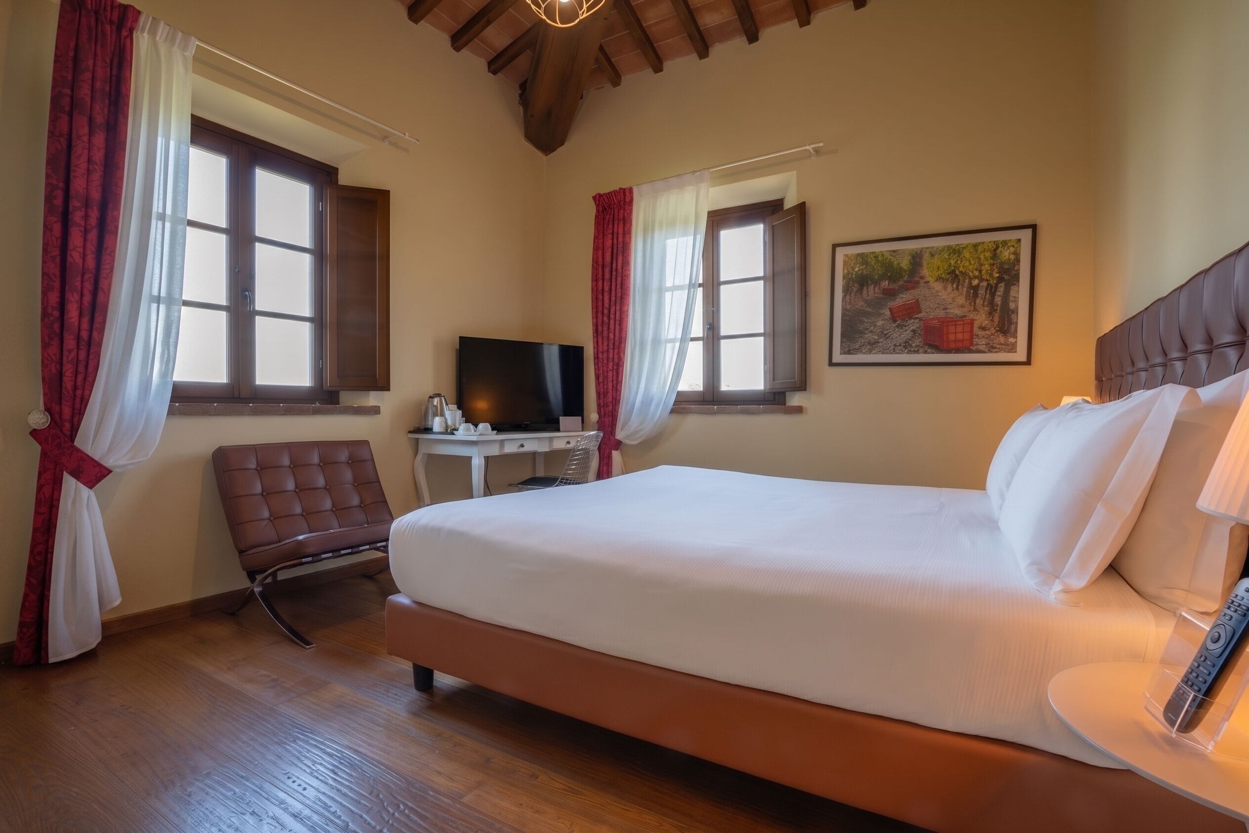 Habitación de hotel con una cama grande, un escritorio con computadora, una silla y un cuadro en la pared.