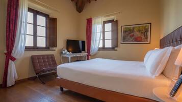 Habitación de hotel con una cama grande, un escritorio con computadora, una silla y un cuadro en la pared.