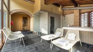 A spa area with two white lounge chairs, a glass-enclosed shower, and a wooden ceiling.