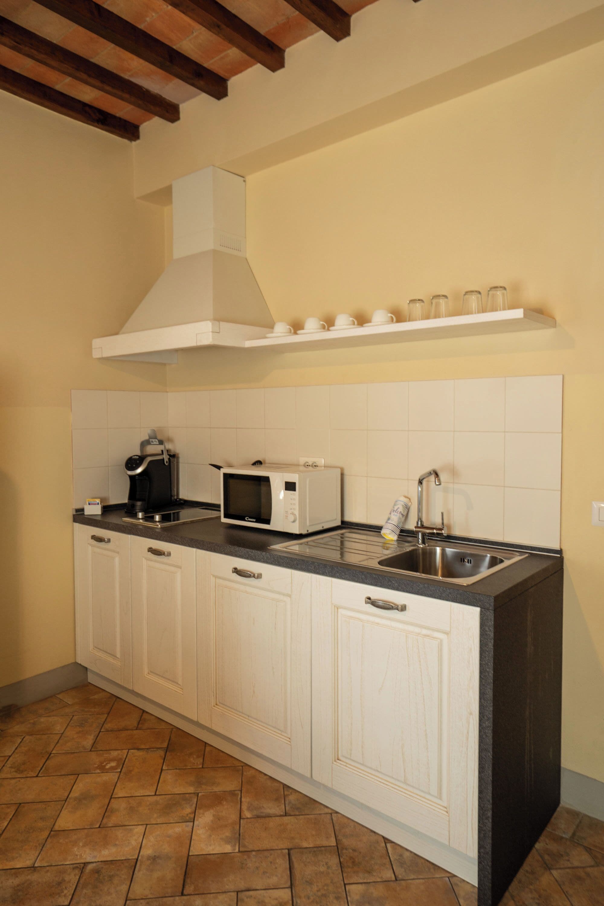A kitchen with white cabinets, a microwave, a coffee maker, and a sink.