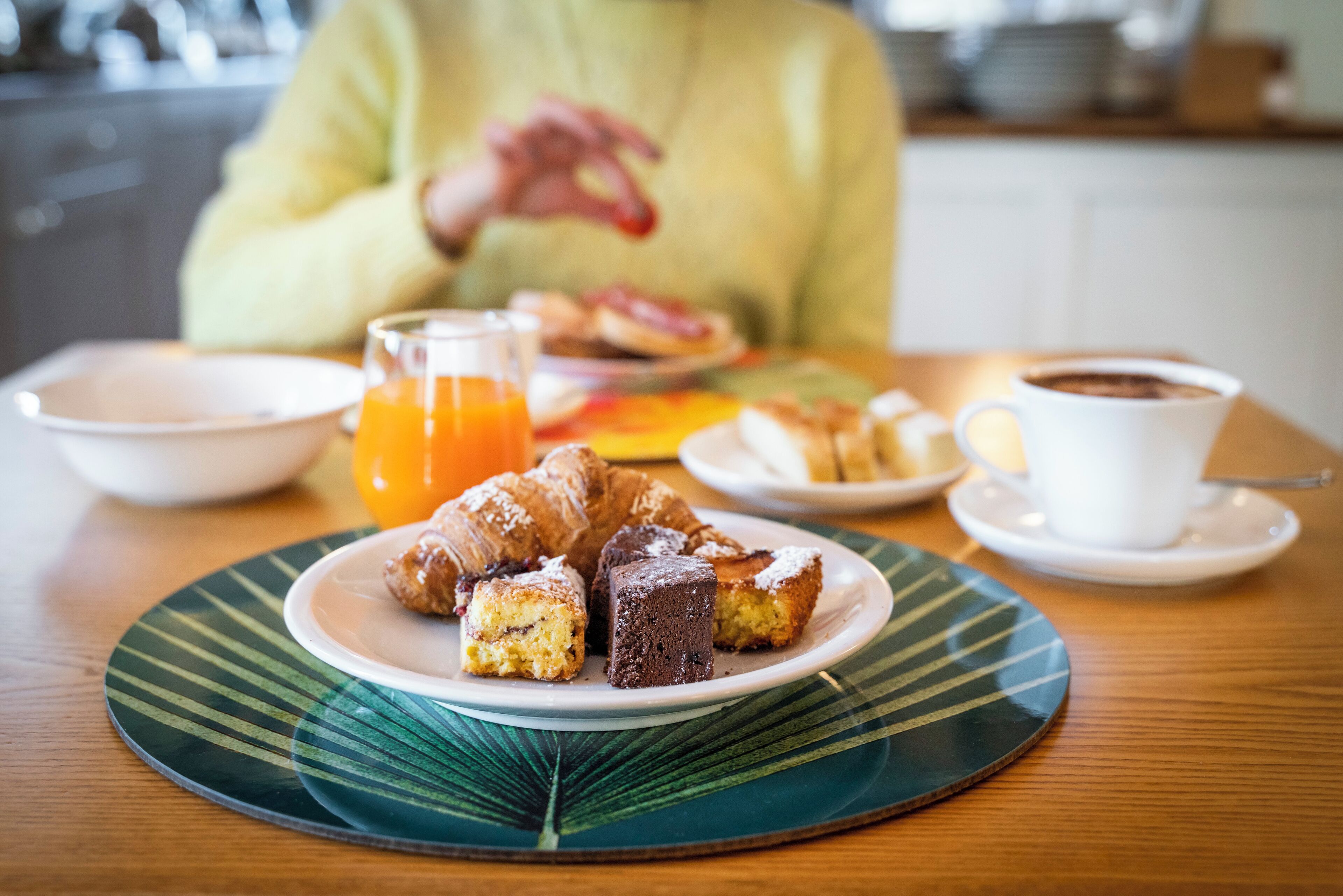 A breakfast setting with pastries, a glass of orange juice, and a cup of coffee on a table.