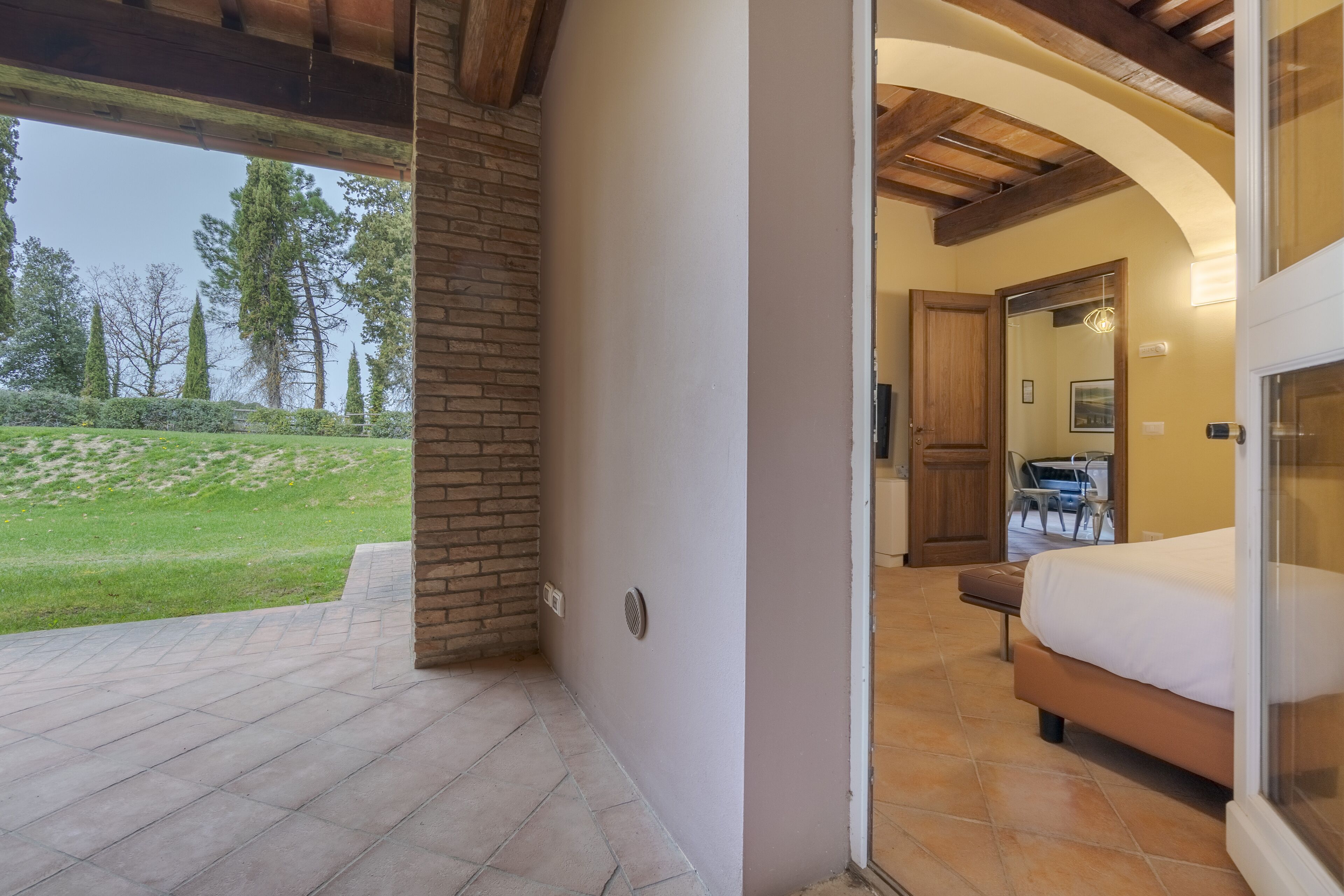 A room with a bed, a small table, and a chair. There is a door leading to another room.