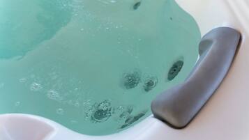 A close-up of a bathtub with a clear blue water feature and a gray bath mat.