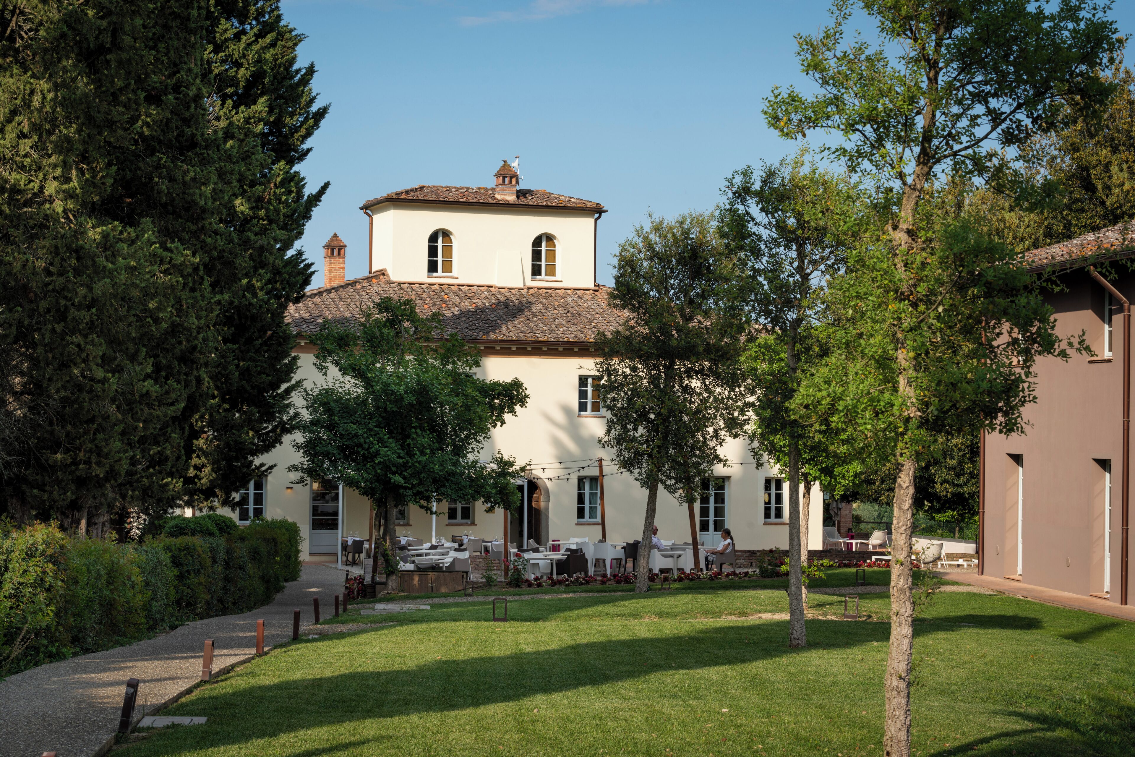 A two-story building with a tiled roof, surrounded by trees and a well-maintained lawn.