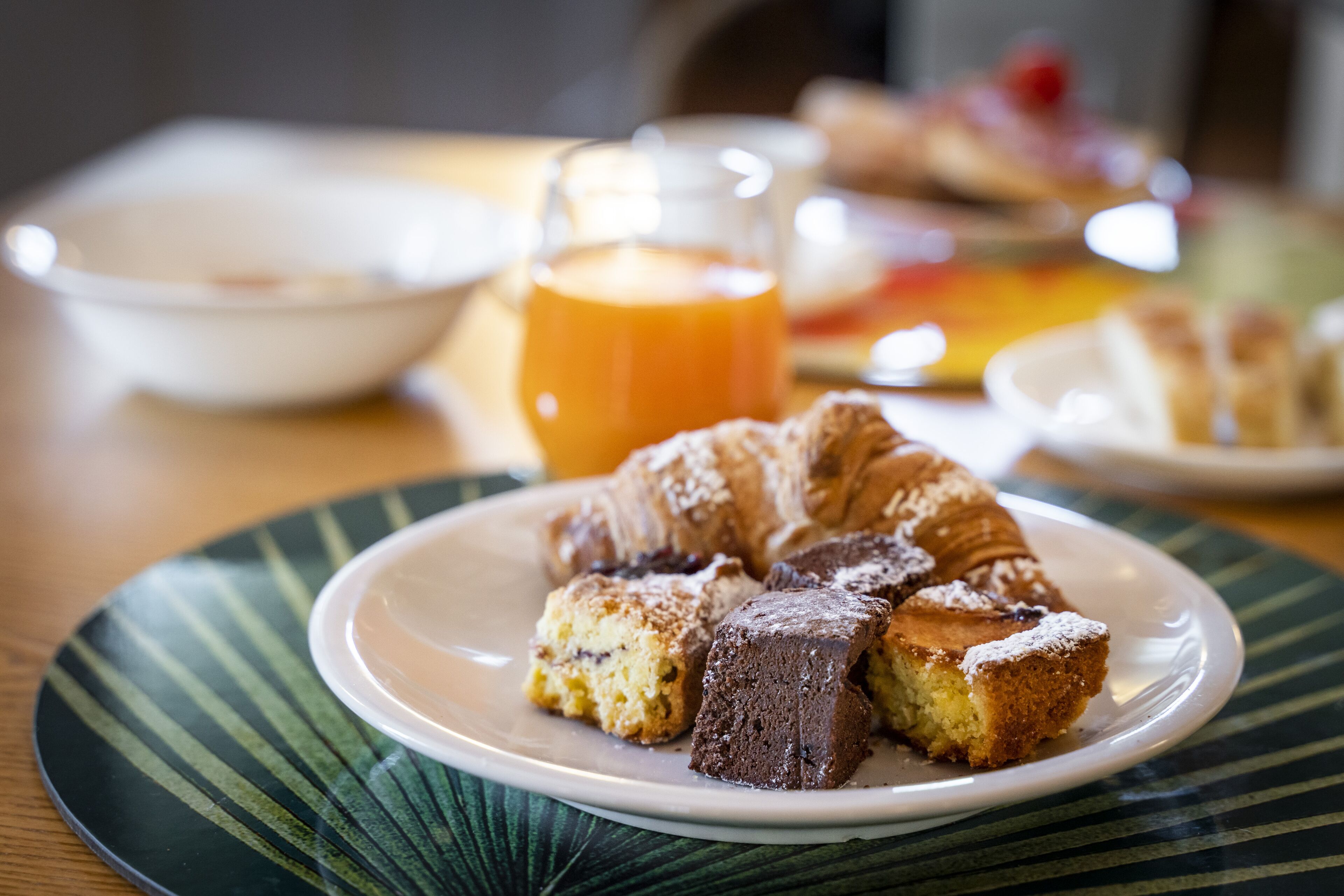 A plate with a piece of cake and a glass of orange juice on a table.