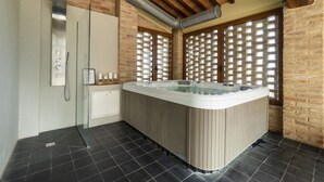 Ein modernes Badezimmer mit Whirlpool, einer Duschkabine aus Glas und einer Ziegelwand.