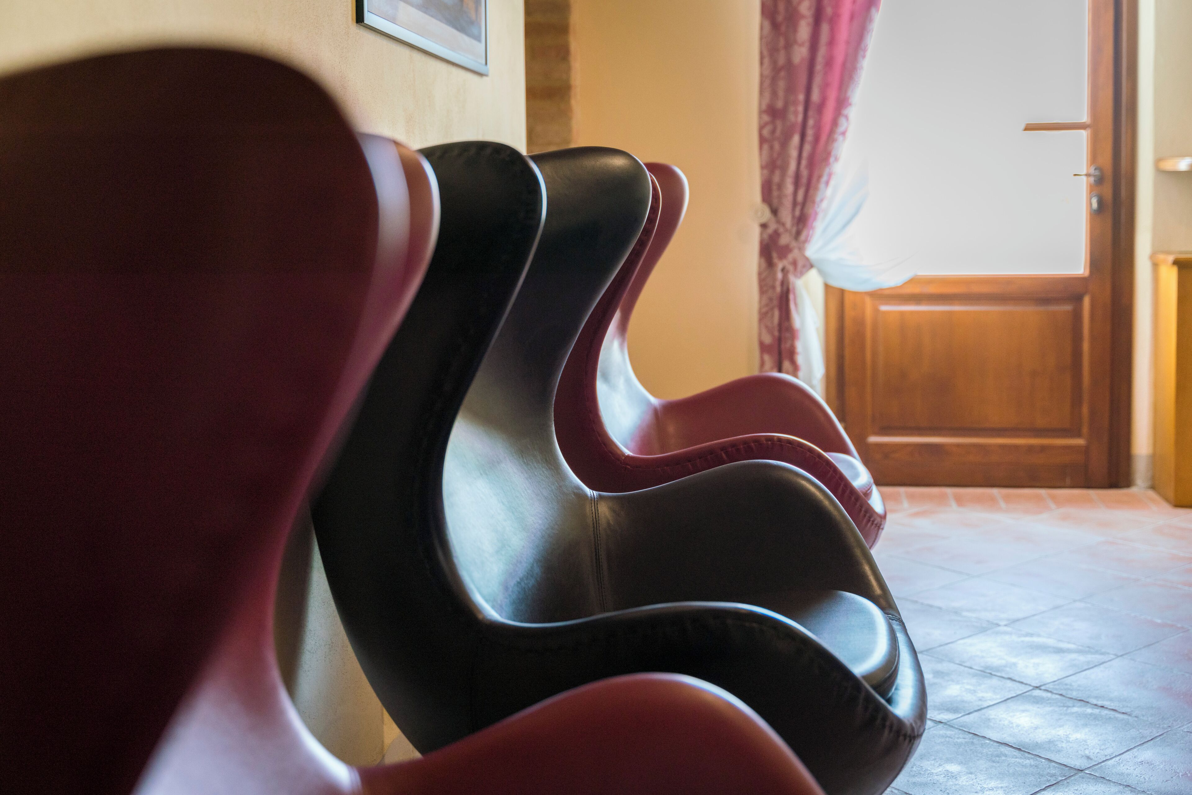 A row of black and red chairs in a room with a tiled floor and a wooden door in the background.