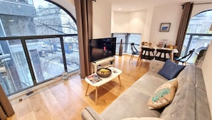 A modern living room with a large TV, a sofa, and a dining area with chairs and a table. - Urban Stay Shard View Apartments (London)