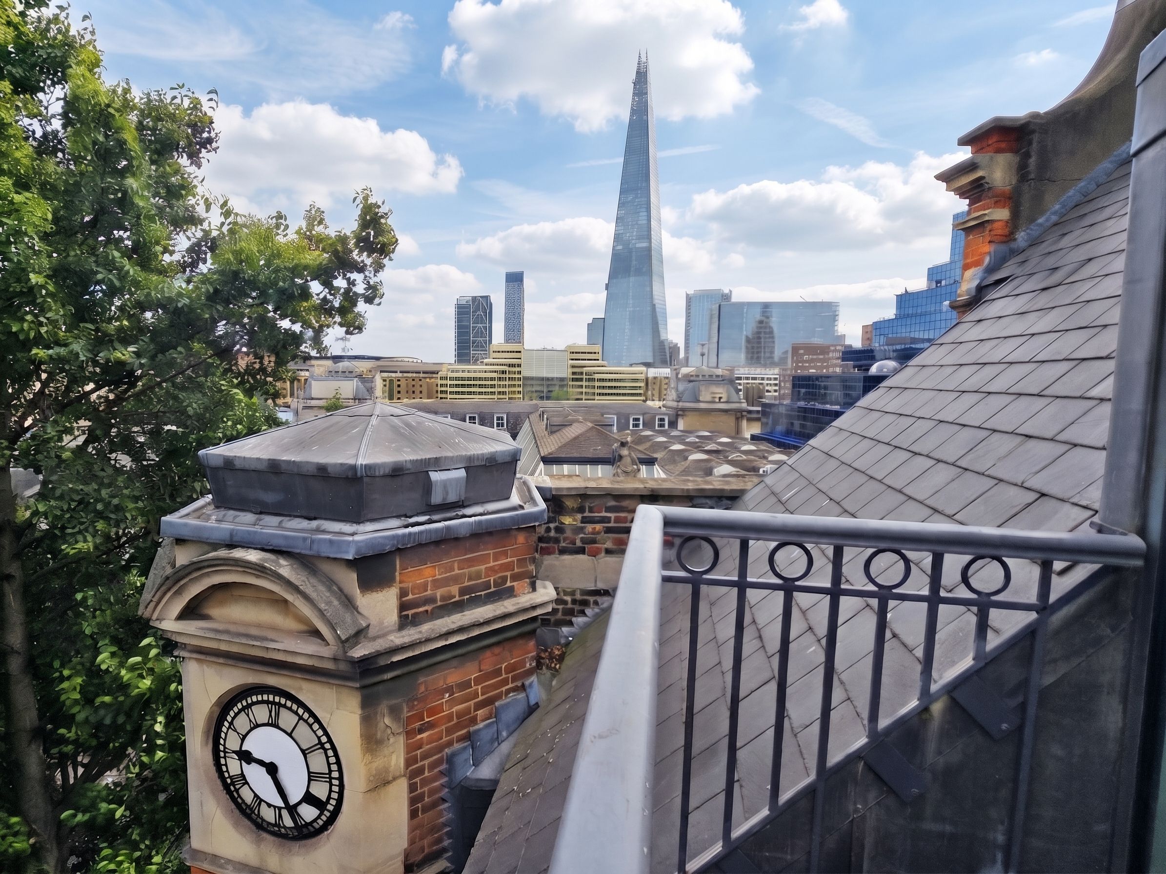 A clock tower with a view of a cityscape, including a prominent skyscraper in the distance.
