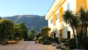 A courtyard with a paved walkway, benches, and potted plants. - Elia Hotel (Buccino)