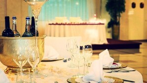 A dining table set with wine glasses, bottles, and cutlery, with a decorative centerpiece and a chandelier in the background. - Elia Hotel (Buccino)