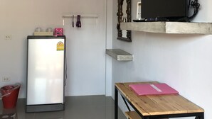 A compact kitchen with a refrigerator, a wooden table, and a mounted TV. - Felice Resort (Koh Lan)