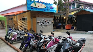 A row of parked scooters in front of a building with a sign that reads "Jebes". - Felice Resort (Koh Lan)
