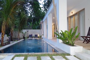 A modern house with a swimming pool, outdoor seating, and lush greenery. - Bali Taman Sari Villa & Restaurant (Negara)