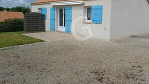 Une maison de plain-pied avec un toit en tuiles, un petit porche à l’avant et une porte de garage.