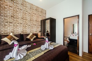 A hotel room with a brick wall, a bed with a patterned bedspread, a nightstand, and a mirror.
