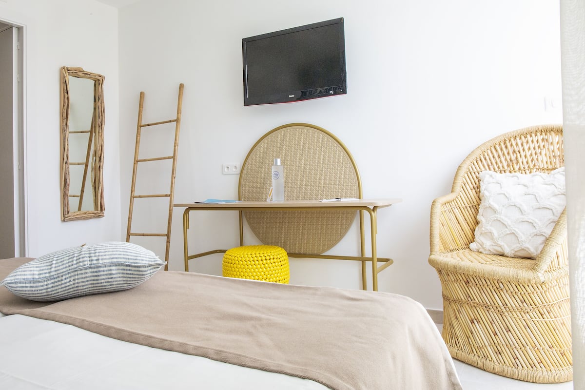 Une chambre à coucher avec un lit, un bureau, une chaise et un téléviseur fixé au mur.