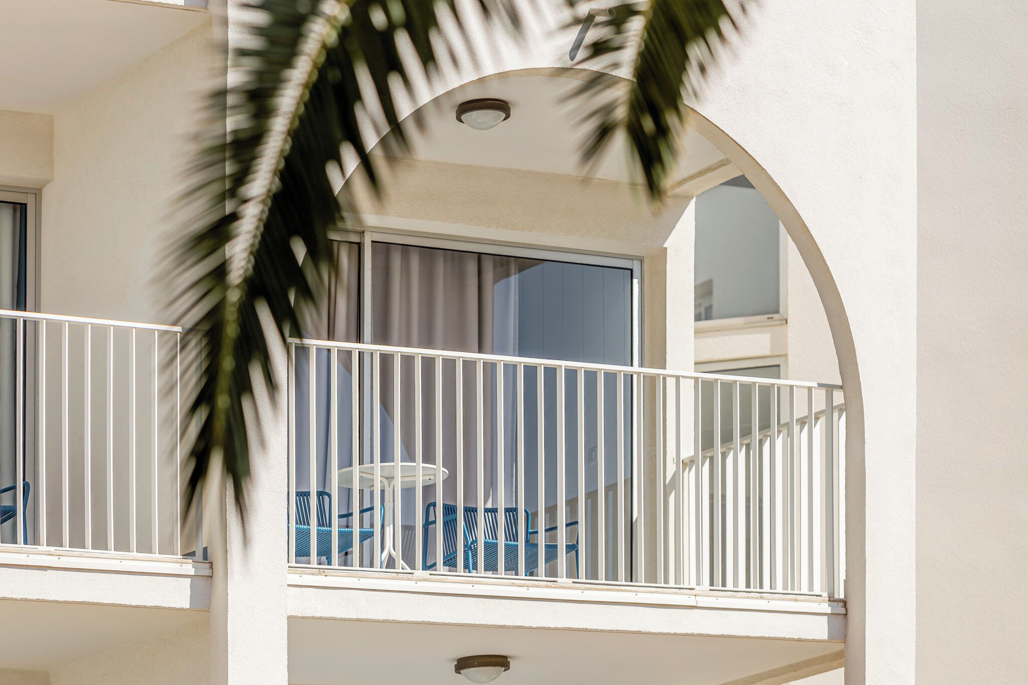 Un balcon avec des balustrades blanches, une table et des chaises bleues.