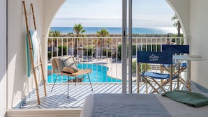 Un balcón con vista al mar, una piscina y mobiliario de exterior.