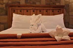 A bed with a plush white bunny toy and a large white flower decoration. - Venados Inn (Mazatlán)