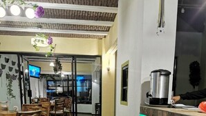 Un restaurant avec un plancher en bois, un comptoir avec une machine à café et un téléviseur fixé au mur.