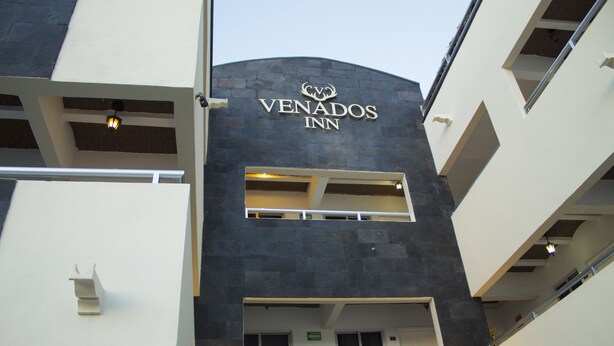 L’extérieur de l’hôtel Venados se distingue par son architecture moderne, avec une enseigne bien visible et un balcon.