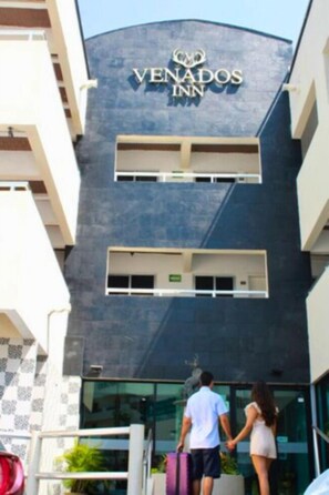 A hotel named 'Venados Inn' with a modern architectural design, featuring a prominent logo and a glass facade. - Venados Inn (Mazatlán)