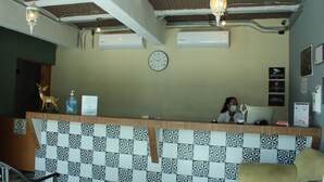 Un espace d’accueil avec un mur recouvert de carreaux, une horloge et un(e) réceptionniste.