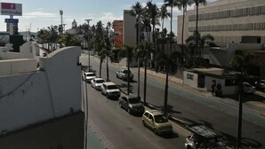 Une vue de rue avec des voitures garées, des palmiers et des immeubles.