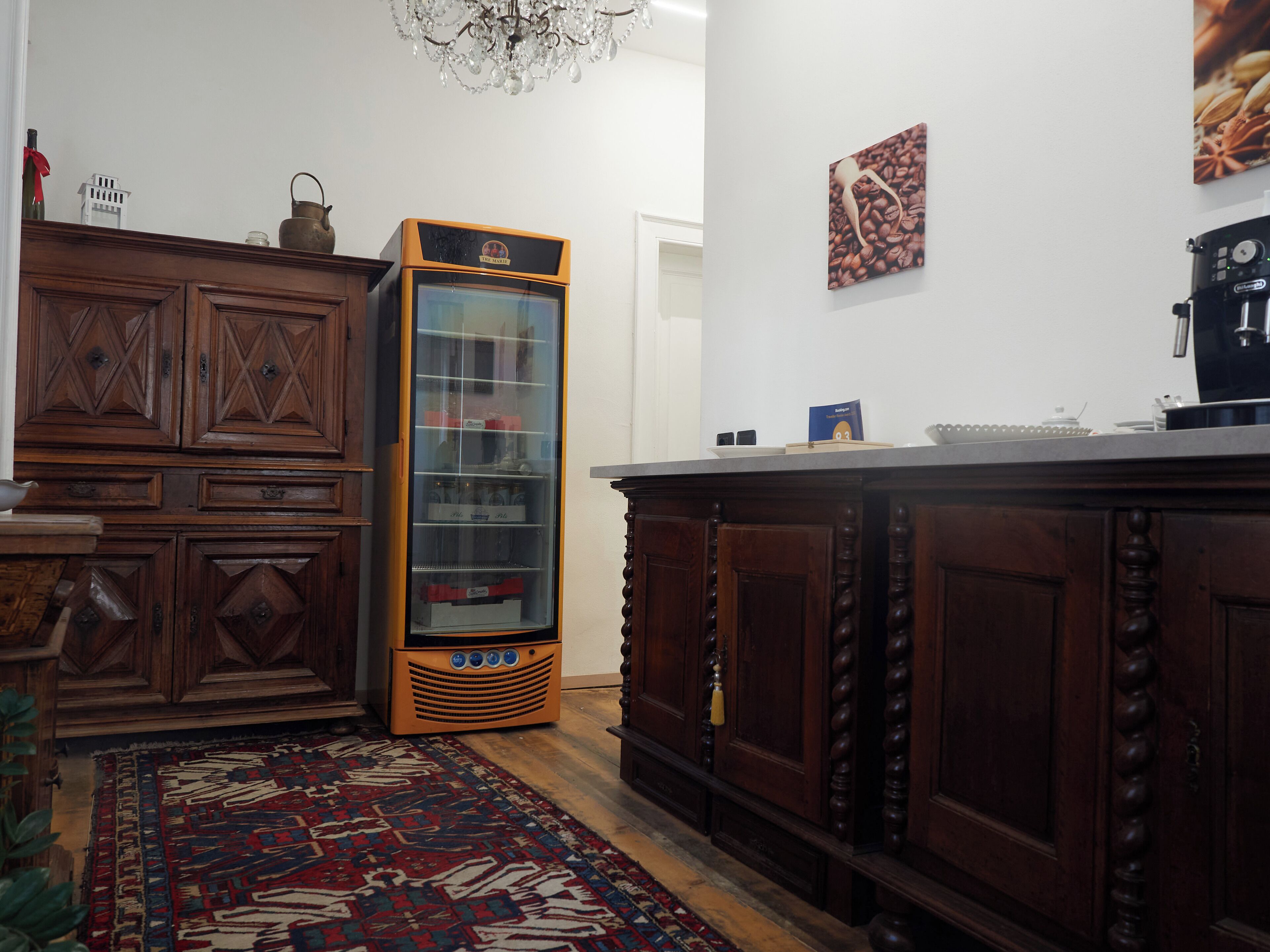 A vintage kitchen with wooden cabinets, a built-in refrigerator, and a patterned rug.