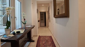 A hallway with a wooden bench, a red patterned rug, and two potted orchids. - La Loggia del Castello (Trento)