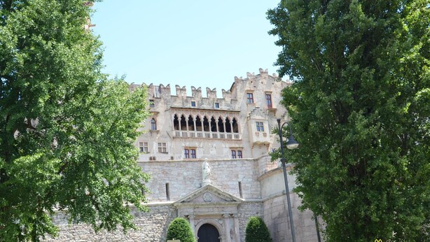A historic building with a stone facade, arched windows, and a central entrance with a statue. - La Loggia del Castello (Trento)
