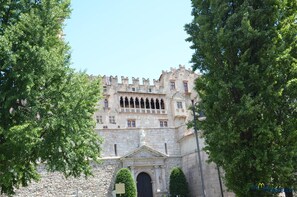 A historic building with a stone facade, arched windows, and a central entrance with a statue. - La Loggia del Castello (Trento)