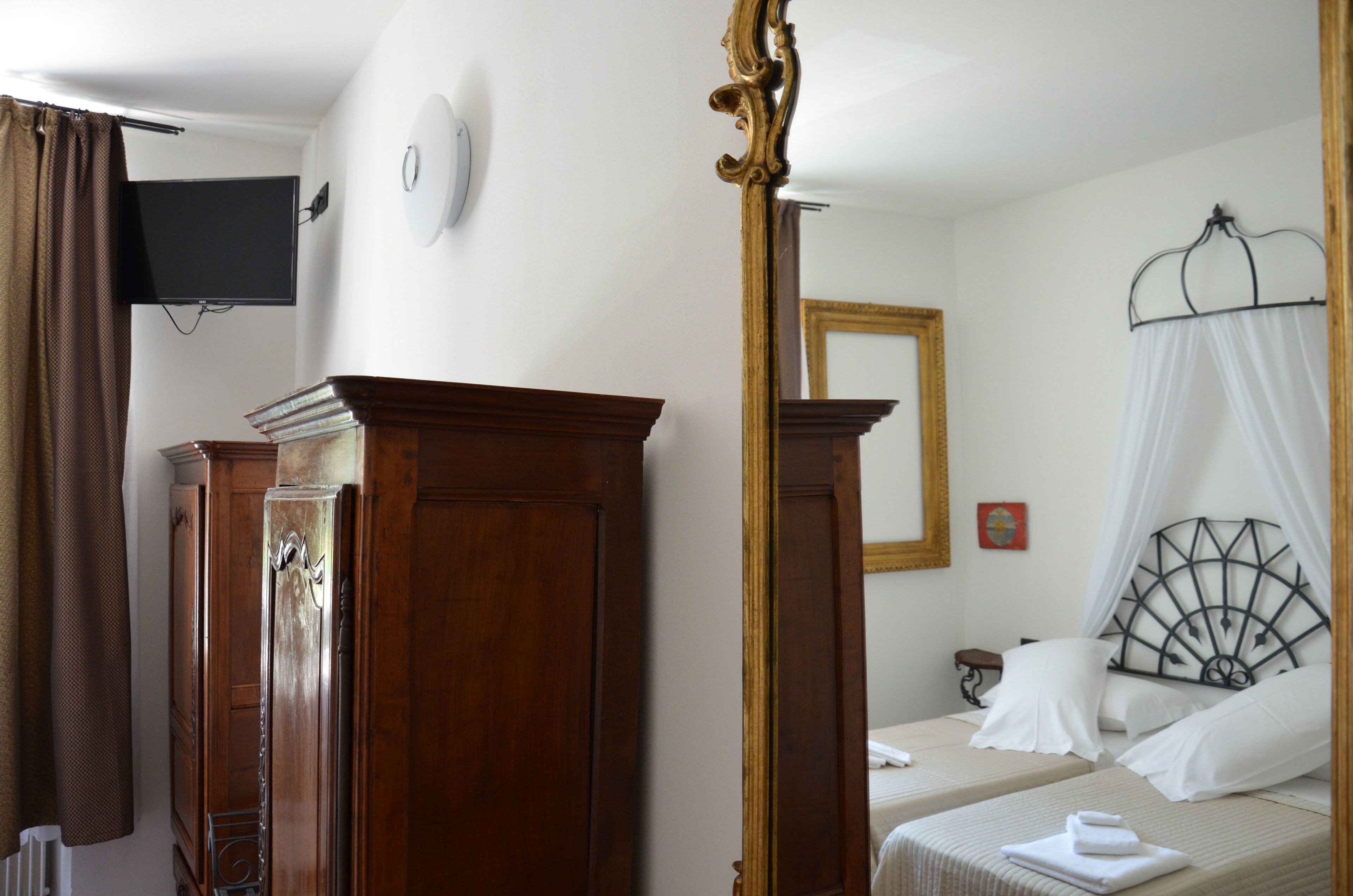 Habitación de hotel con cama, televisor, armario y espejo.