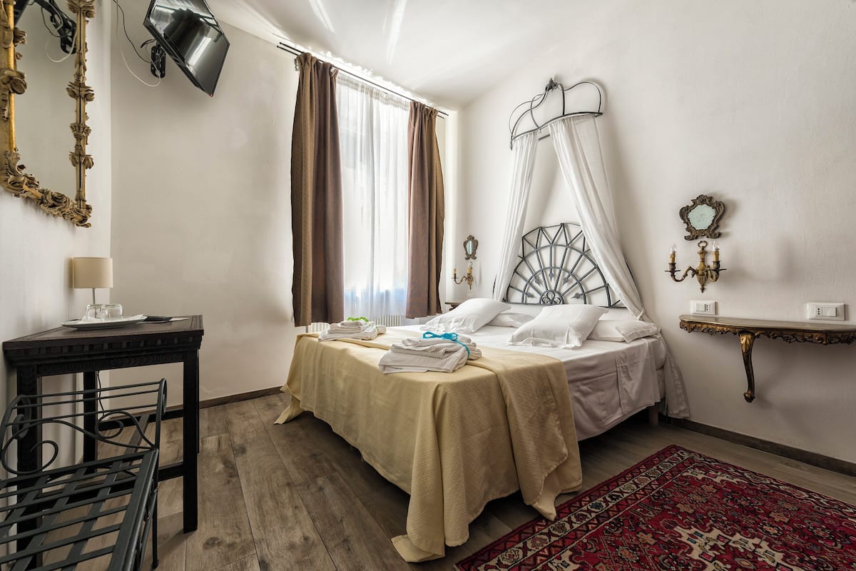 A bedroom with a bed, bedside table, lamp, and a chair.