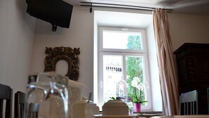 A dining table with a cake, a glass pitcher, and a potted orchid by a window. - La Loggia del Castello (Trento)
