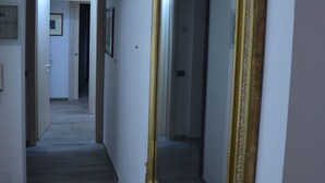 A hallway with a large ornate mirror, a wooden door, and a patterned rug. - La Loggia del Castello (Trento)