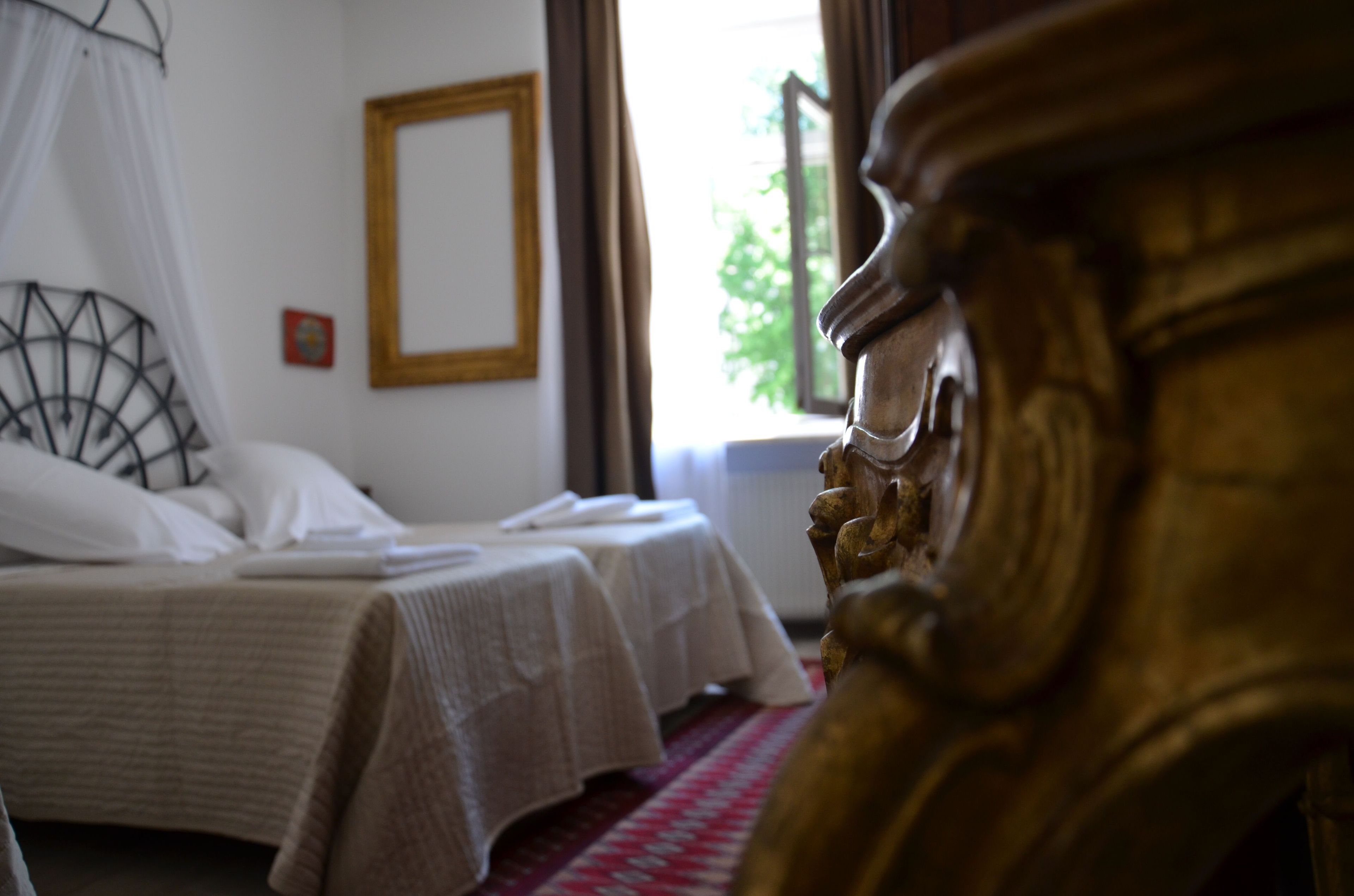 A room with two beds, a large window, and a decorative wooden headboard.