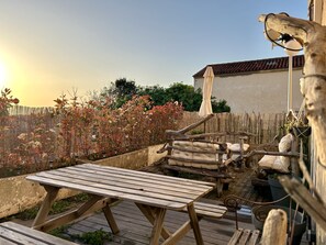 A wooden deck with a picnic table, a rustic wooden bench, and a hanging light fixture.