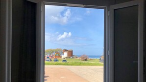 Una ventana con vista a un estacionamiento, un edificio con decoraciones coloridas y un cielo despejado.