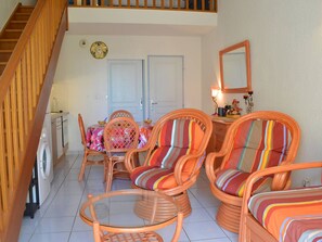 Uma sala de estar ampla com móveis de vime, uma mesa de jantar e uma máquina de lavar roupa.