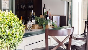 Un espace bar avec un comptoir en bois, des bouteilles de vin, des verres et une plante en pot.