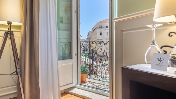 Une chambre d’hôtel avec un balcon, une plante en pot et une enseigne indiquant le Lisbon Wine Hotel.