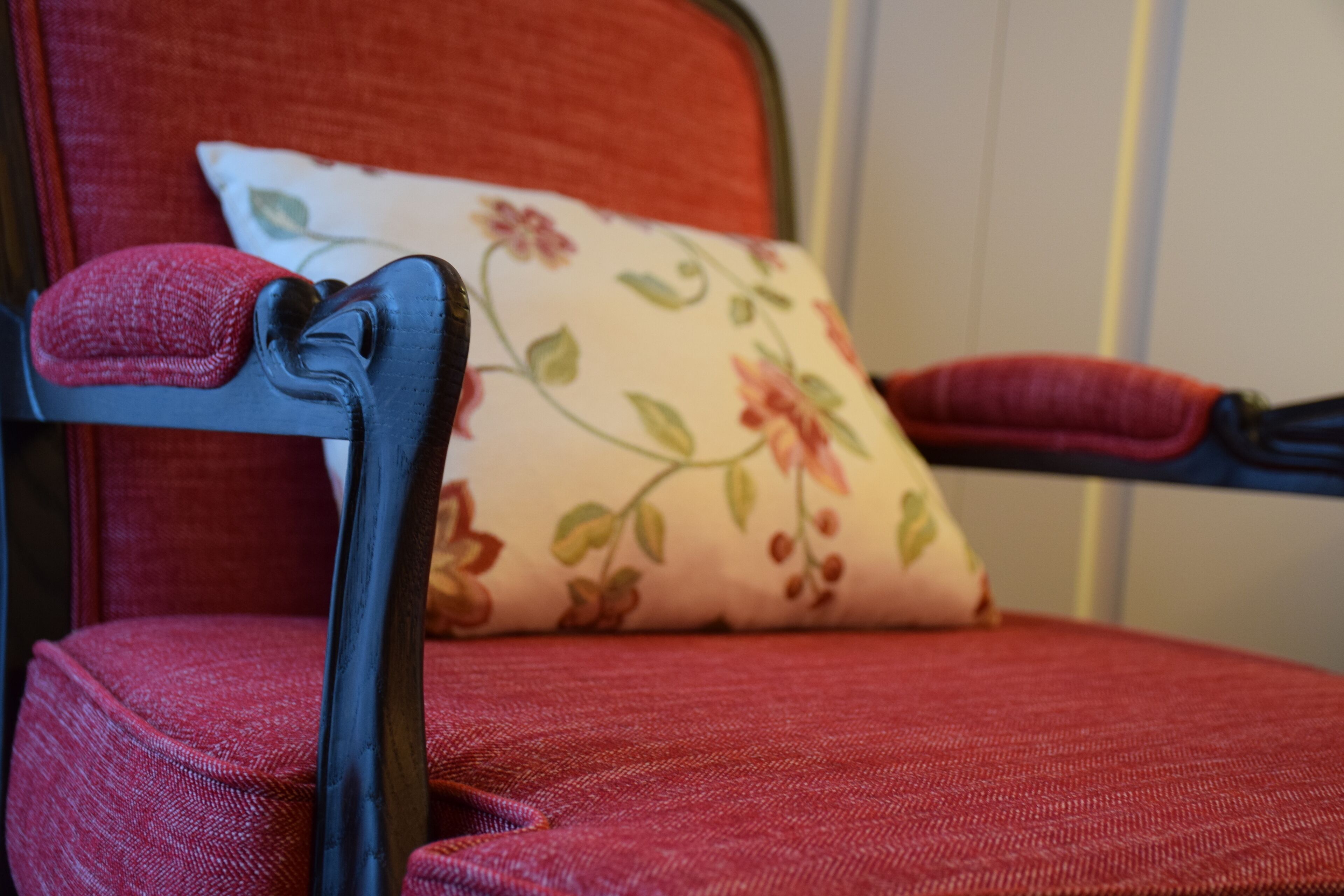 Ein Detailaufnahme eines roten Sitzmöbels mit einem Blumenkissen.