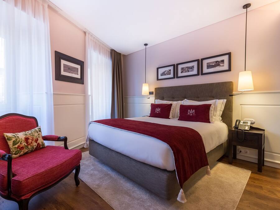 Een keurig opgemaakt slaapkamer met een bed, een stoel, een nachtkastje en een lamp.