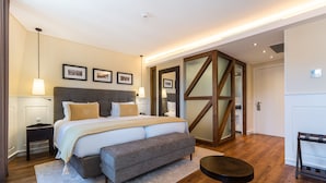 Une chambre moderne avec un grand lit, des tables de chevet, un banc et une petite table.