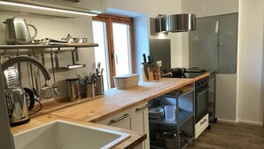 A modern kitchen with a wooden countertop, stainless steel appliances, and a built-in oven. - Kraeuterhof-Ferienwohnung (Missen-Wilhams)