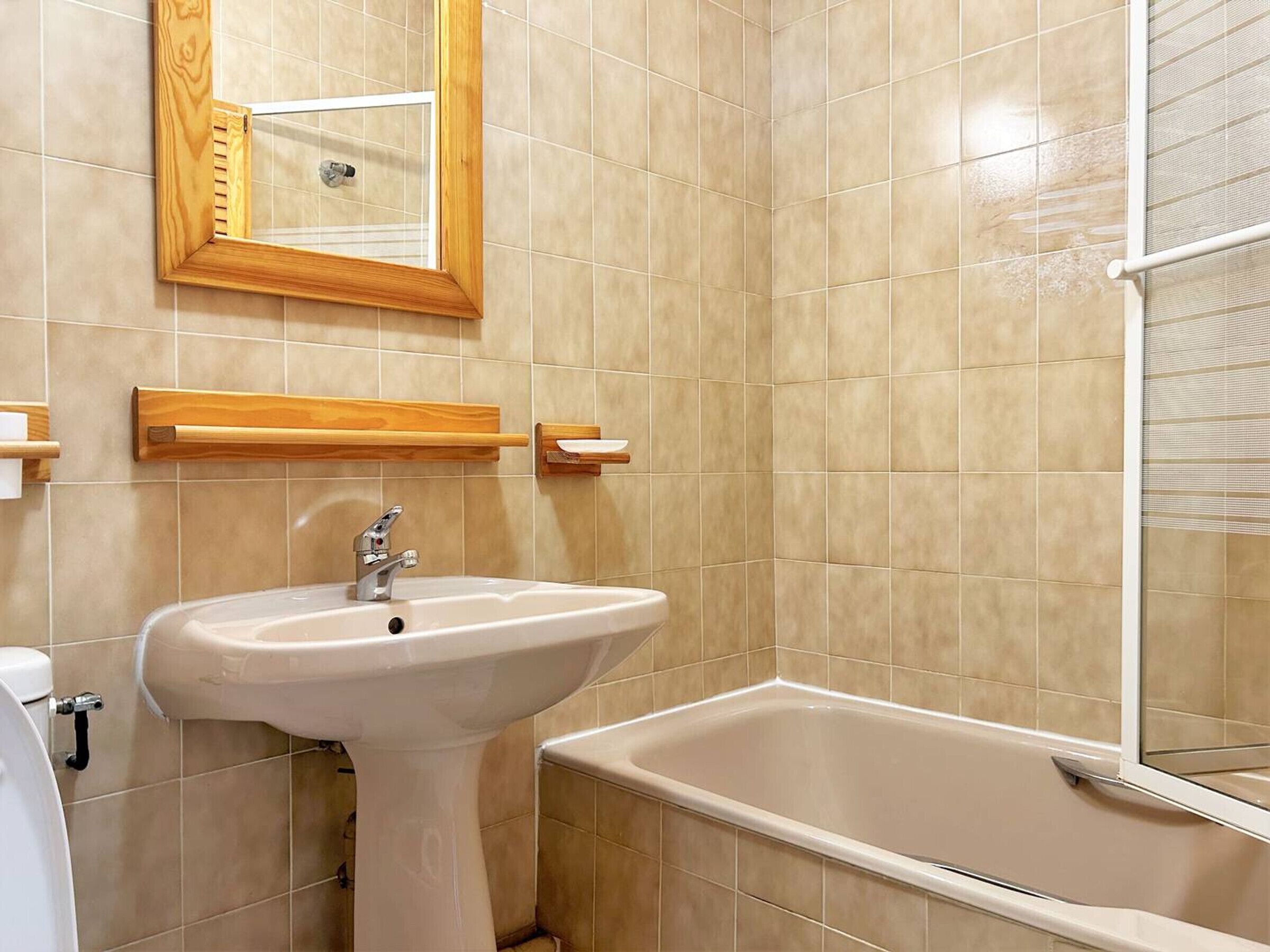 A bathroom with a white sink, a mirror, and a bathtub.