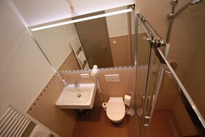 Une salle de bain équipée d’un lavabo, de toilettes et d’une douche à parois de verre.